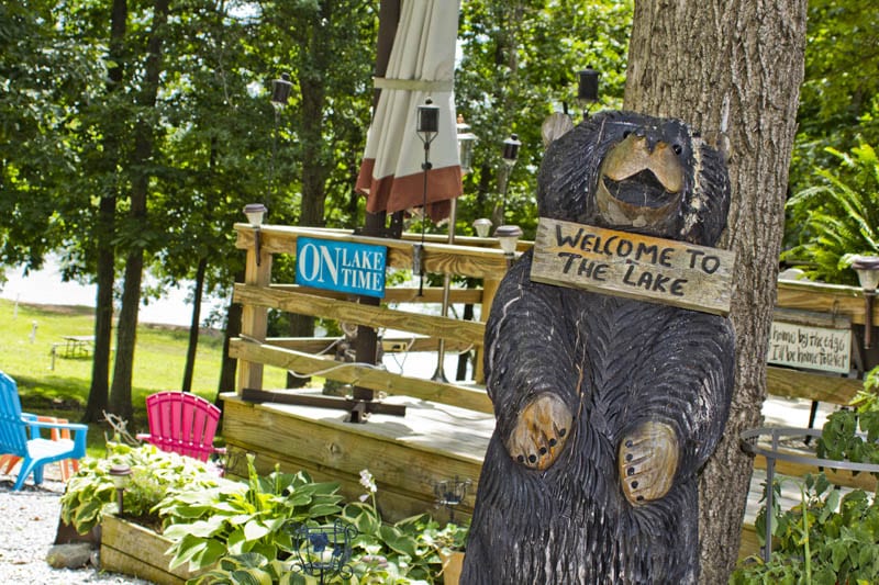 Campground bear statue. Text: Welcome to the Lake, On Lake Time.